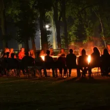 Deelnemers rond een kampvuur in het donker