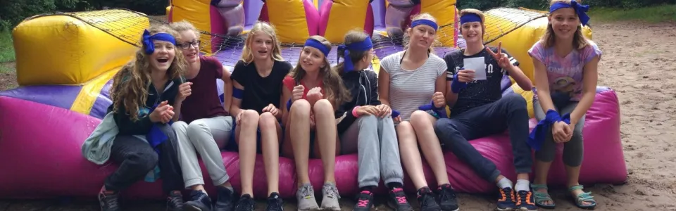 Deelnemers zitten samen op een groot springkussen