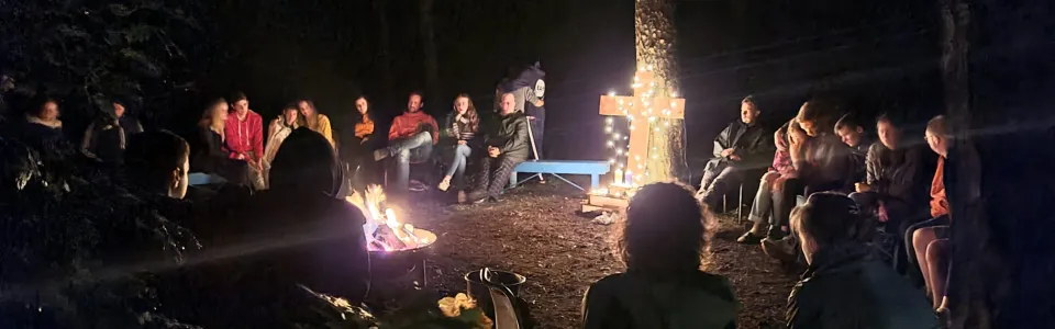 Kampvuur in het donker met deelnemers eromheen