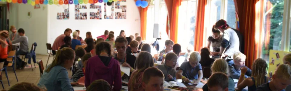 Volle zaal met vlaggetjes tijdens een kampactiviteit
