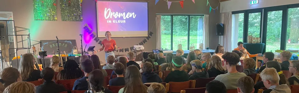 Tieners luisteren samen naar een kleurrijke podiumviering tijdens brugkamp1
