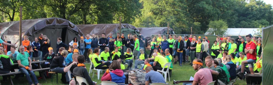 Deelnemers zitten op stoelen buiten voor de tent