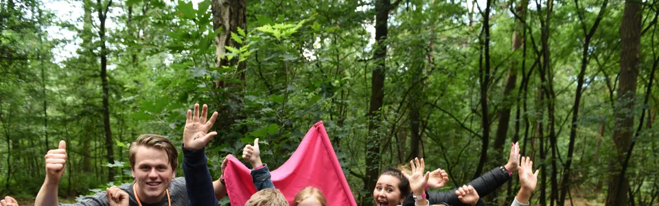 Kampleider en kinderen juichen in het bos