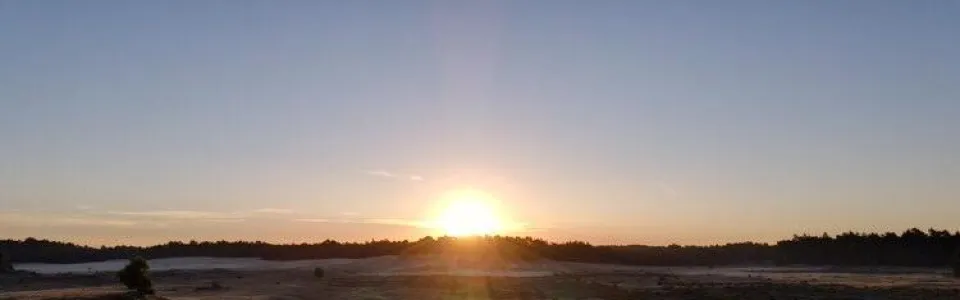 Zonsondergang boven de zandvlakte met deelnemers