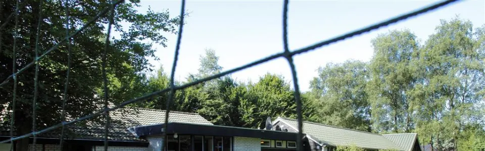 Kampgebouw achter een sportveld met net
