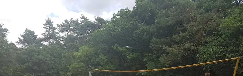 Deelnemers spelen volleybal op het zandveld