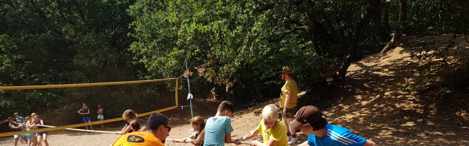 Deelnemers spelen volleybal op het zandveld