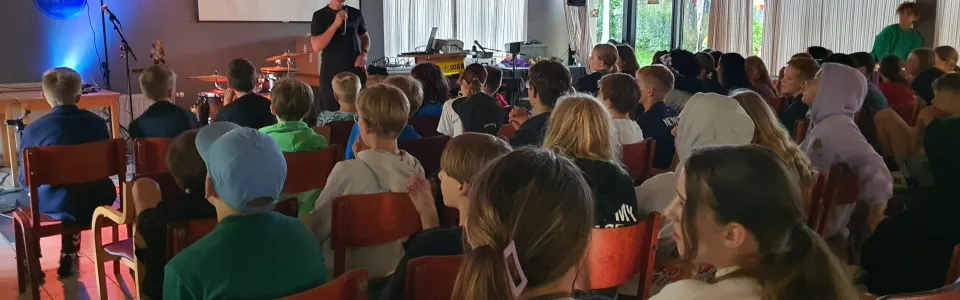 Deelnemers in de zaal met blauw licht op het podium