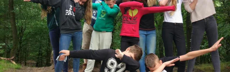 Deelnemers doen samen een dansje in het bos
