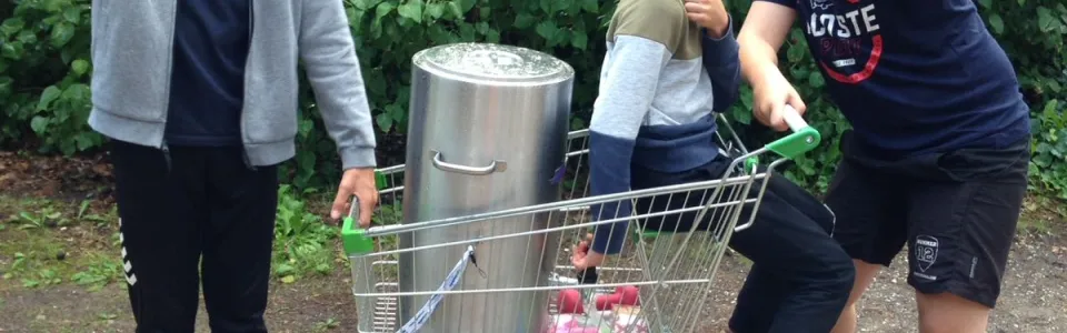 Deelnemers duwen een winkelwagen over het terrein