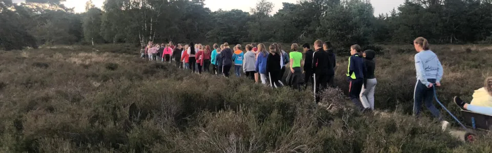 Deelnemers in een zaal met oranje vlaggetjes tijdens Koningsspelen