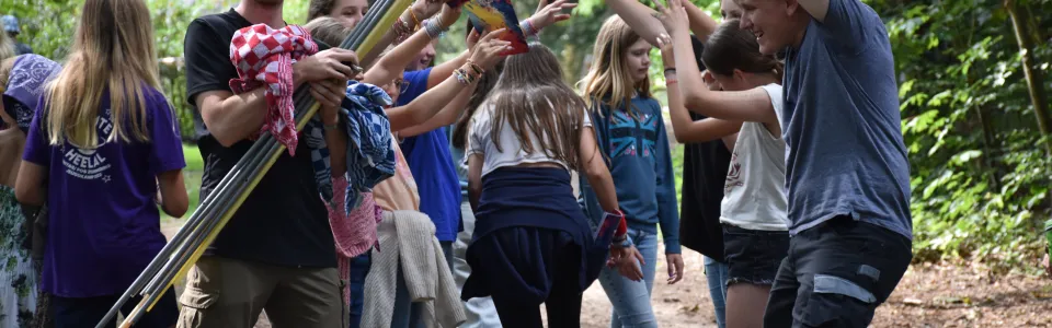 Deelnemers spelen een spel met stokken en linten