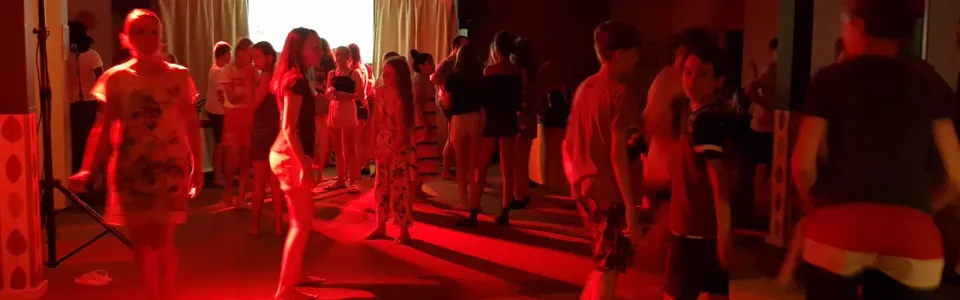 Deelnemers dansen in een zaal met rood licht