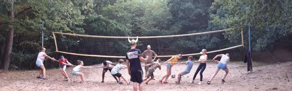 Deelnemers spelen volleybal op het zandveld