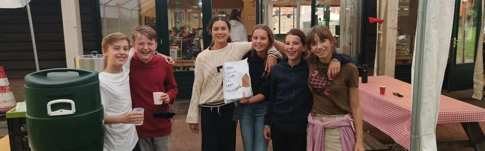 Deelnemers poseren in de tent bij het kampgebouw