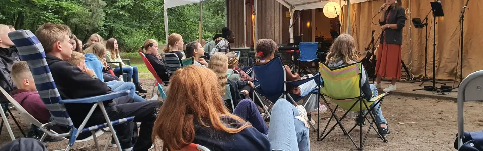 Deelnemers zitten in stoelen op het terrein bij aankomst