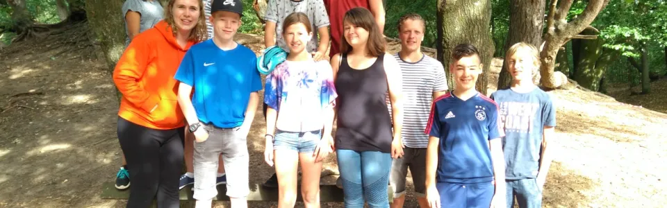 Groep deelnemers poseert tussen de bomen
