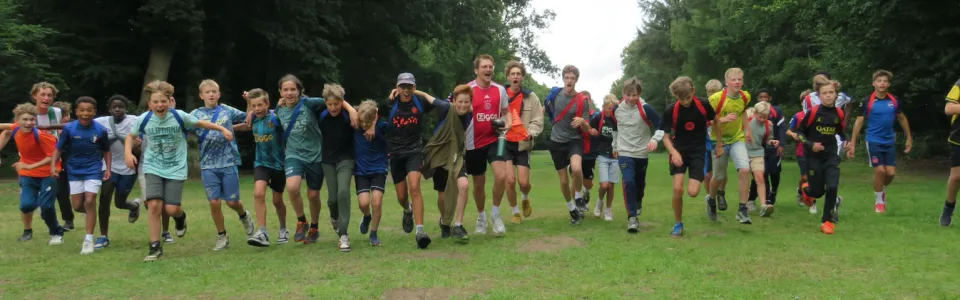 Deelnemers staan in een grote kring op het grasveld