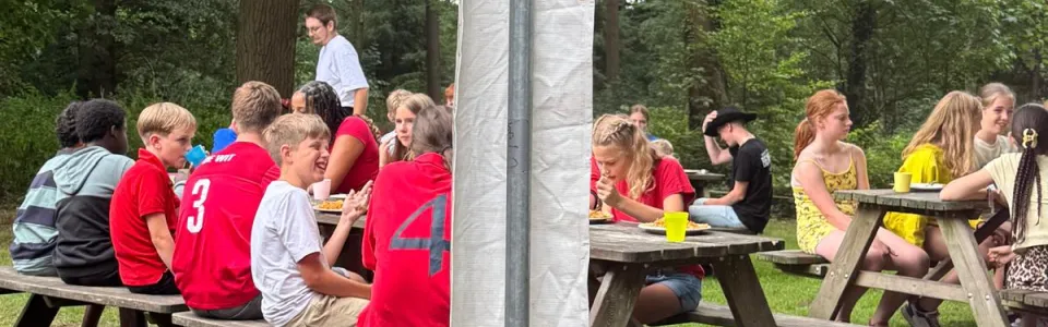 Deelnemers bij picknicktafels onder een parasol