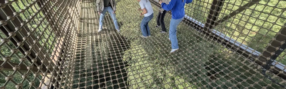 Deelnemers klimmen in een net onder een speeltoestel