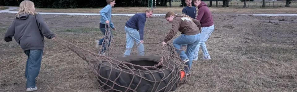 Deelnemers slepen een grote band over het veld