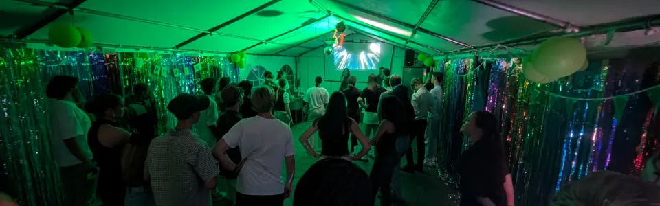 Deelnemers dansen in een tent met groen licht
