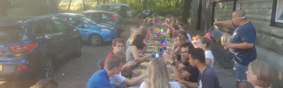 Deelnemers eten aan lange tafels buiten