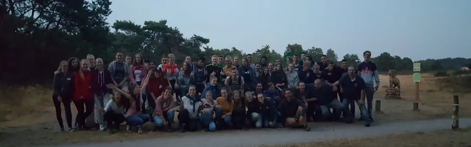 Grote groep deelnemers op de zandvlakte bij avondlicht