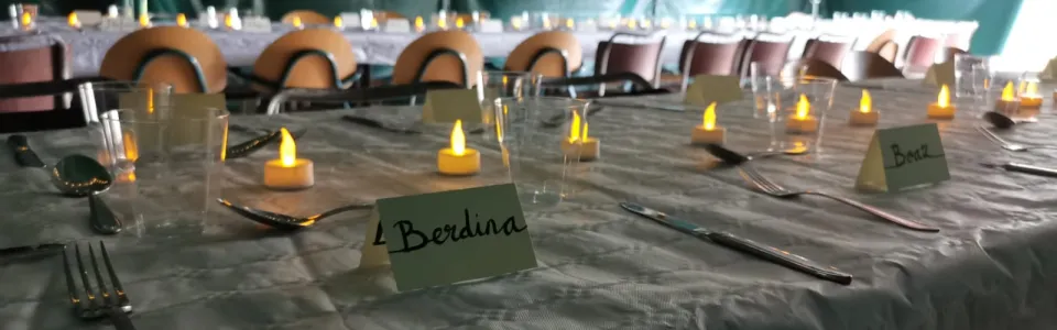 Gedekte tafel met kaarsjes en naamkaartjes onder vlaggen