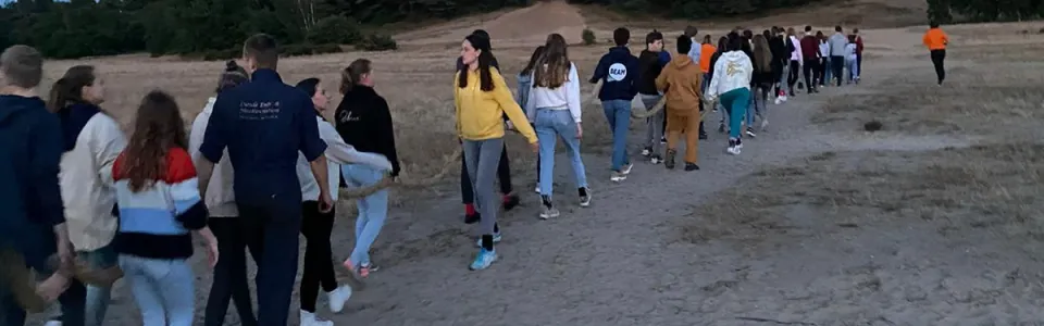 Deelnemers lopen in een rij tijdens de avondwandeling