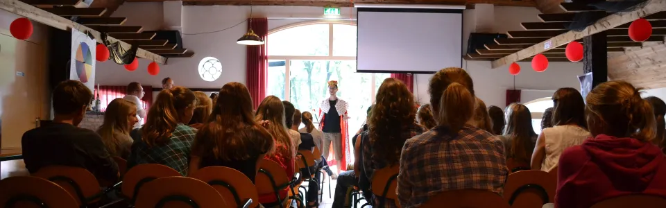 Volle zaal deelnemers kijkt naar een presentatie op het scherm