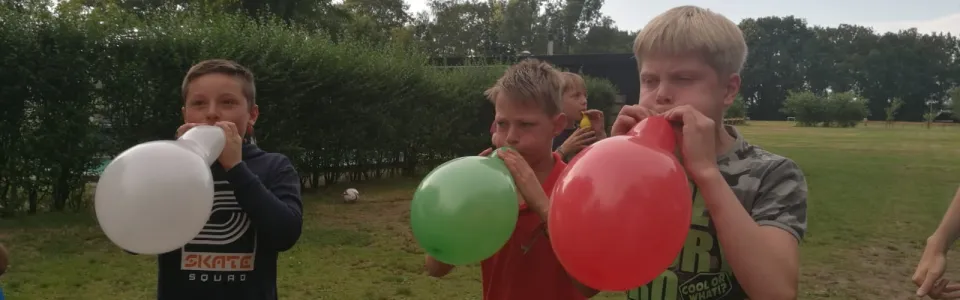 Kinderen blazen ballonnen op in het gras