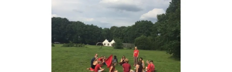 Deelnemers zitten in een kring op een grasveld