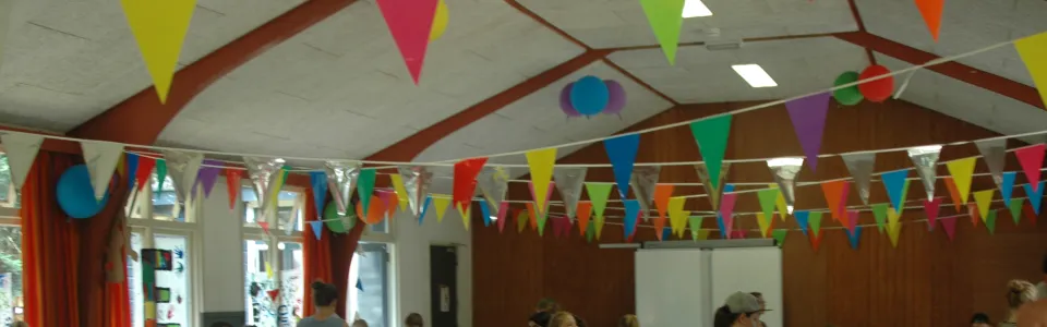 Deelnemers aan tafels in een zaal met vlaggetjes