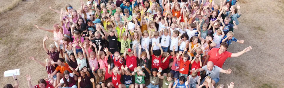 Deelnemers liggen in een grote groep op de grond, van bovenaf gezien