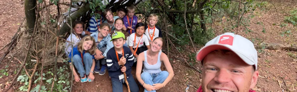 Kampleider maakt een selfie met deelnemers bij een hut