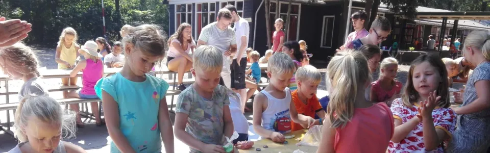 Kinderen knutselen aan lange tafels