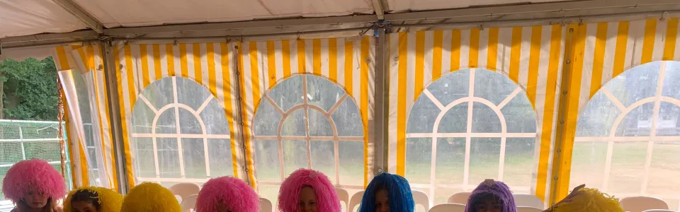 Deelnemers met gekleurde pruiken op een rij