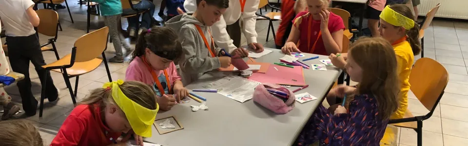 Kinderen knutselen aan tafels in de zaal