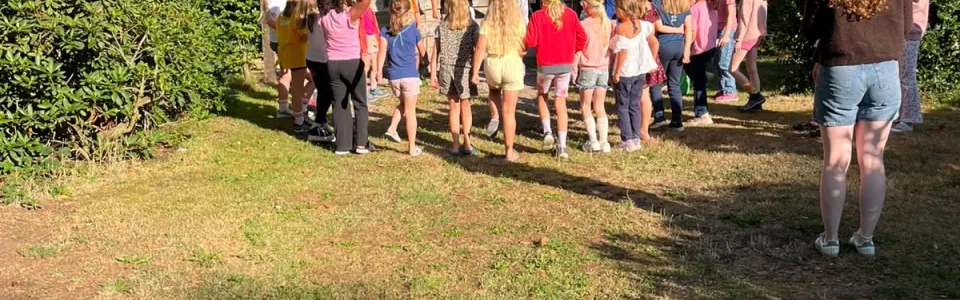 Deelnemers lopen in een rij langs de bosrand