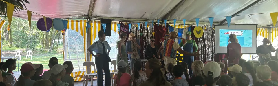 Deelnemers zitten onder de partytent tijdens het programma