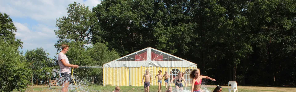 Deelnemers glijden over een nat zeil
