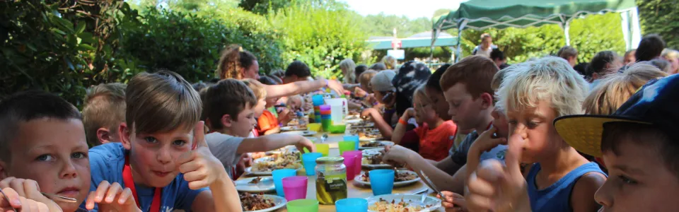 Deelnemers eten aan een lange gedekte tafel
