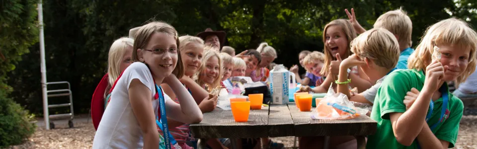 Kinderen aan een lange tafel met eten en drinken