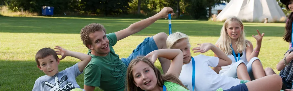 Kinderen liggen in het gras voor de tenten