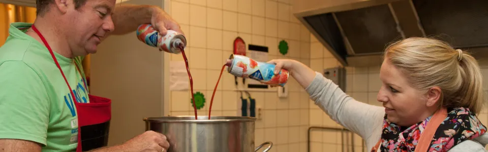 Kampleider schenkt limonade in een pan, een meisje kijkt toe