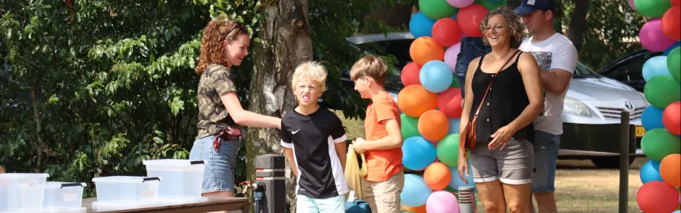 Kinderen arriveren met hun ouders onder een vrolijke ballonnenboog