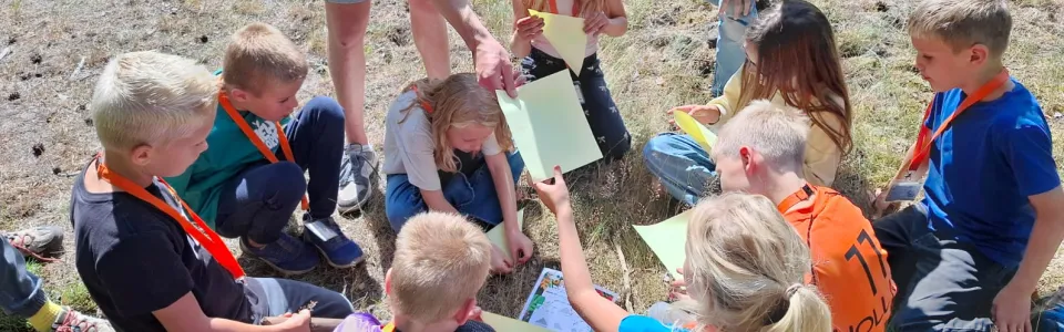 Kinderen lossen samen met hun leiding een bosopdracht op