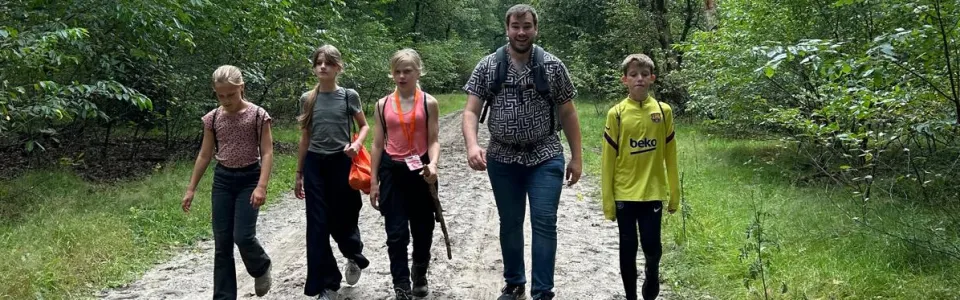 Vier kinderen wandelen met hun begeleider over een bospad