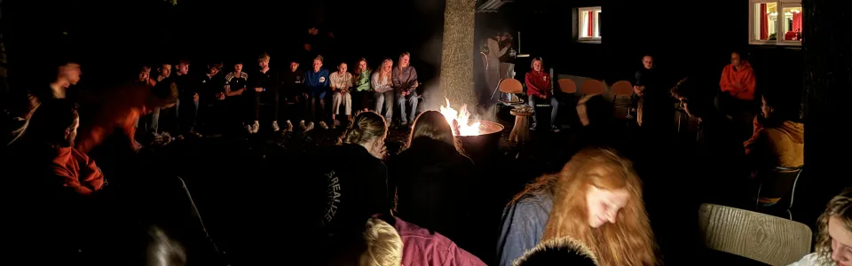 Deelnemers rond een kampvuur in het donker